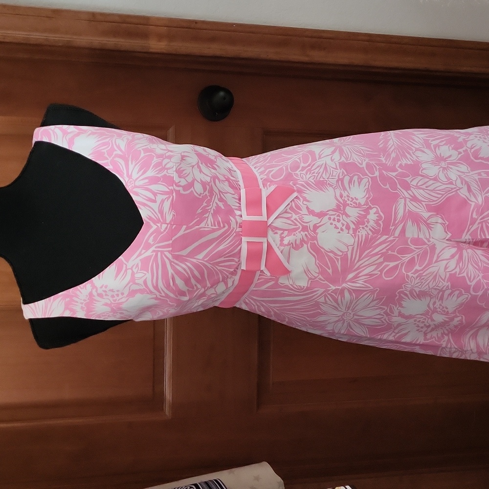 Pink floral and white dress with bow at waist and pleat in front of dress.